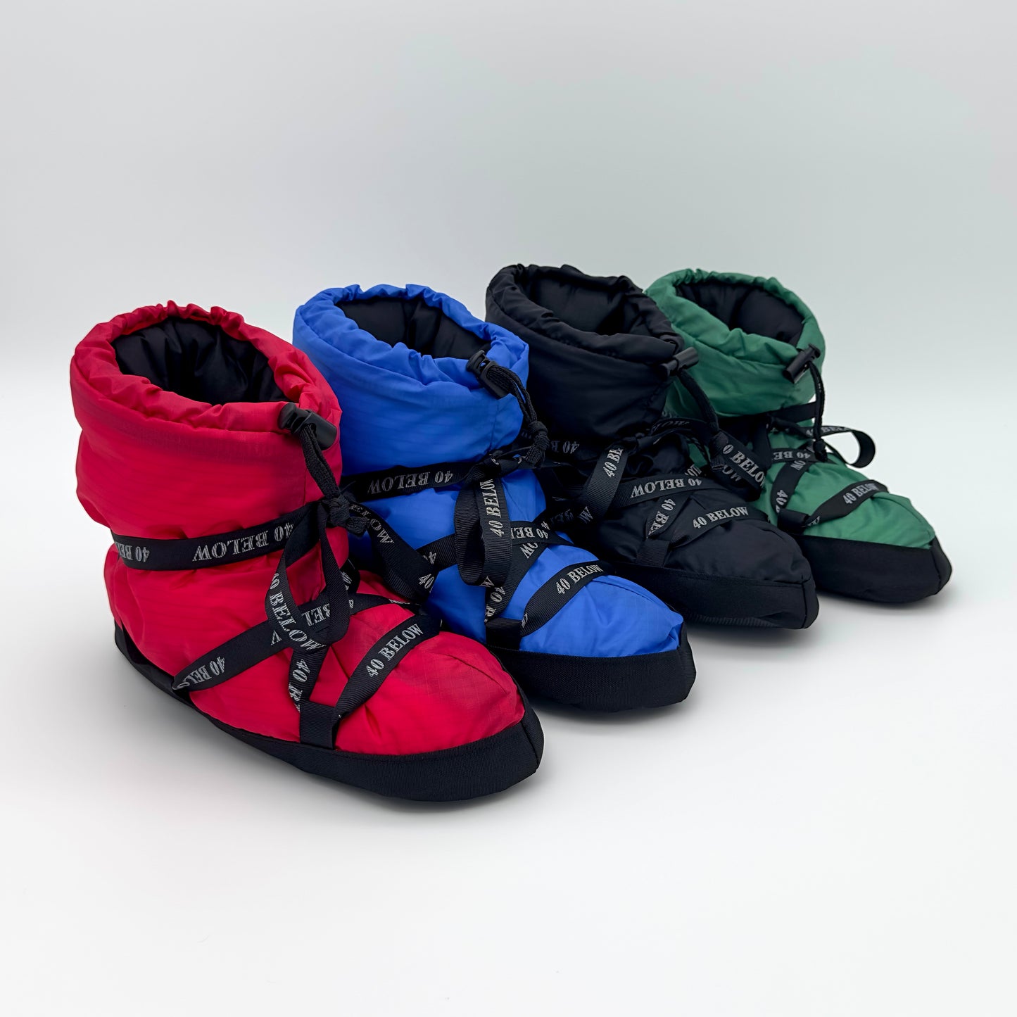 Forty Below Insulated Camp Bootie red, blue, black, and green colors next to eachother with black ribbon lacing on a white backdrop